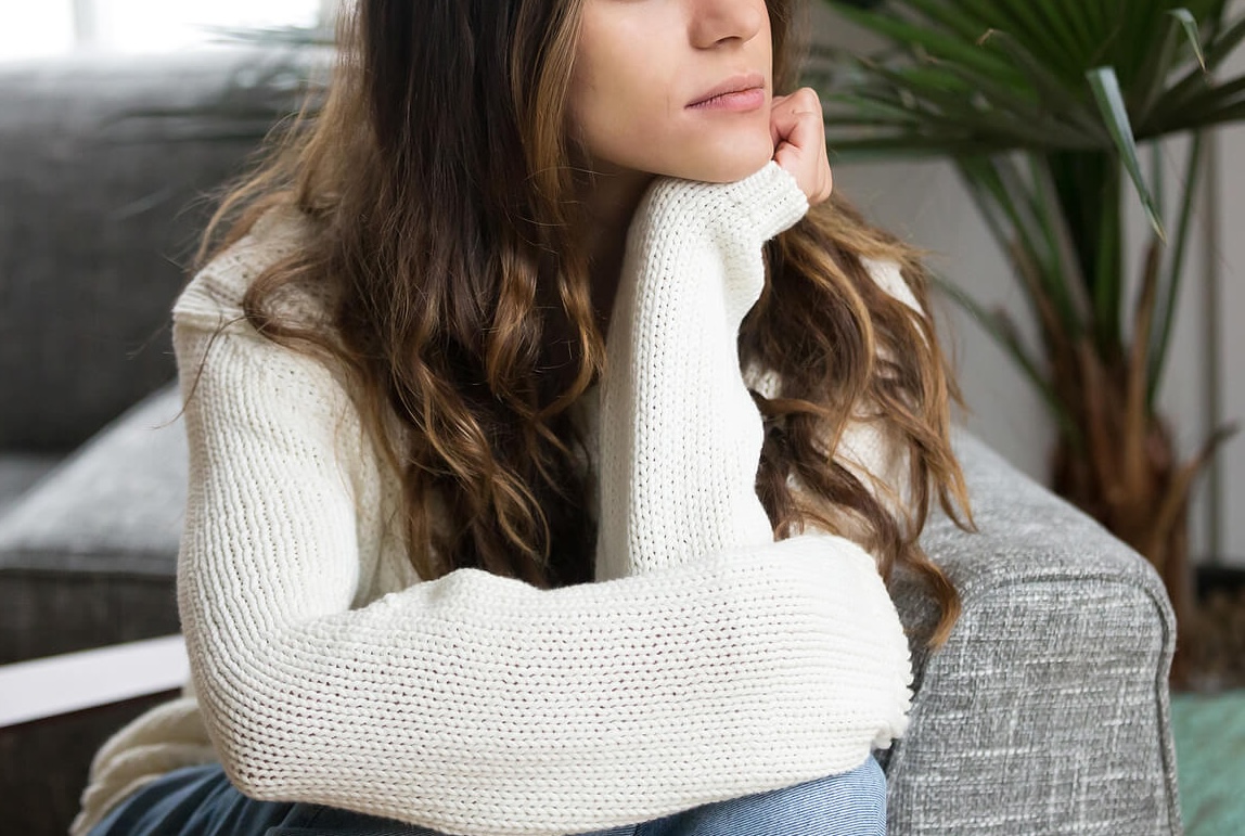 Image of a woman sitting in a chair resting her chin on her hand in thought. Find support in setting boundaries during the holidays with the help of a skilled trauma therapist. Set boundaries with trauma therapy in South Jersey.