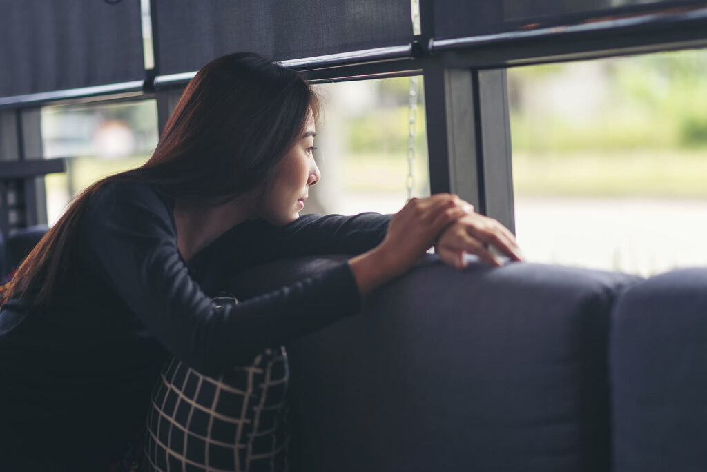 Image of a peaceful woman sitting on a couch looking out a window. Give yourself some self compassion during the new year with the help of therapy in South Jersey.