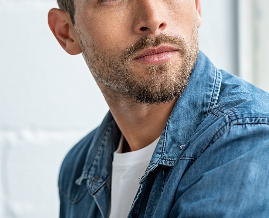 Image of a peaceful man looking out a window wearing a denim shirt. Find self compassion with the help of therapy in South Jersey and give yourself grace during the new year.