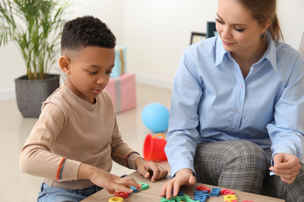 Image of a smiling professional adult woman playing with a young boy. Help your child cope with their emotions as children or teens with the support of skilled therapist in therapy for children and teens in South Jersey.