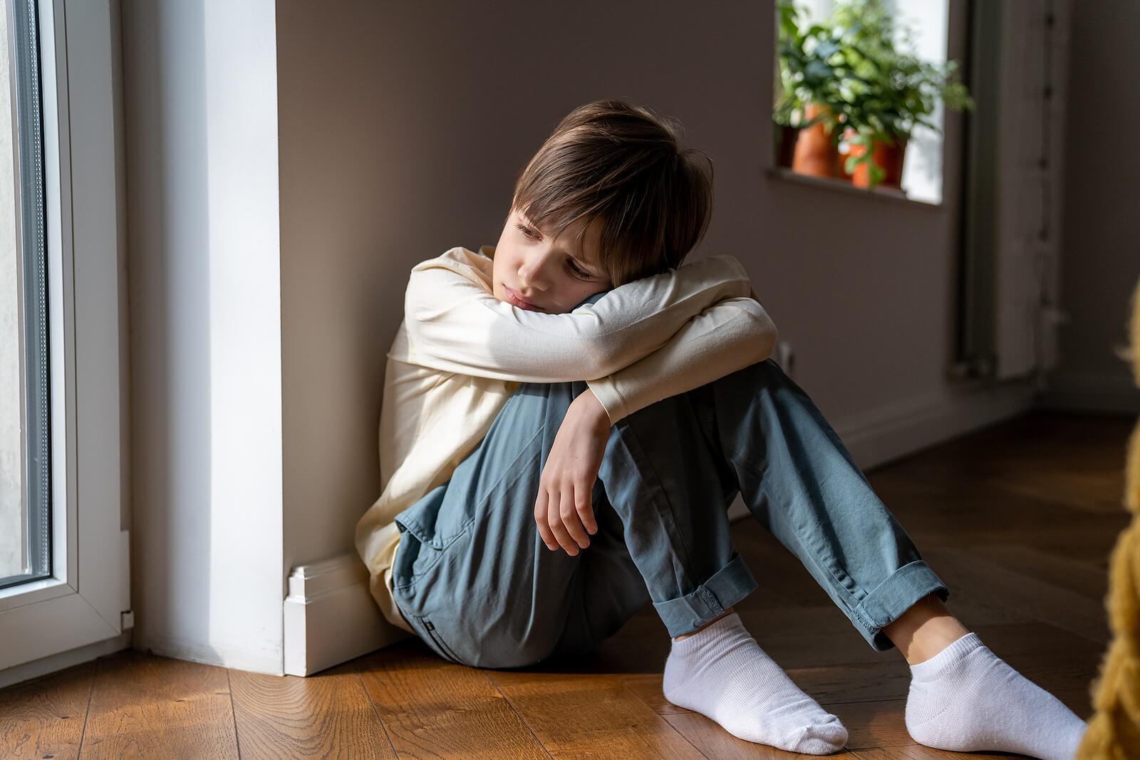 Sad boy sitting on the floor resting his head on his knees. If your child struggles with depression and their emotions, find support with therapy for children in South Jersey.
