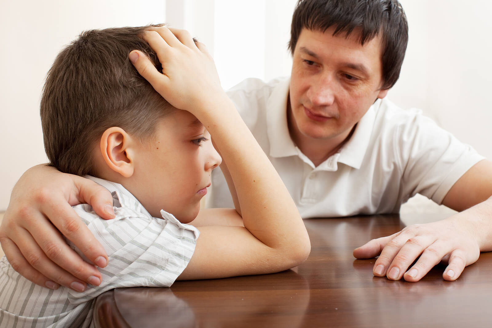 Father putting his arm around his upset young son to comfort him. With therapy for children in South Jersey your child can begin to manage their overwhelming emotions and take charge of their lives.