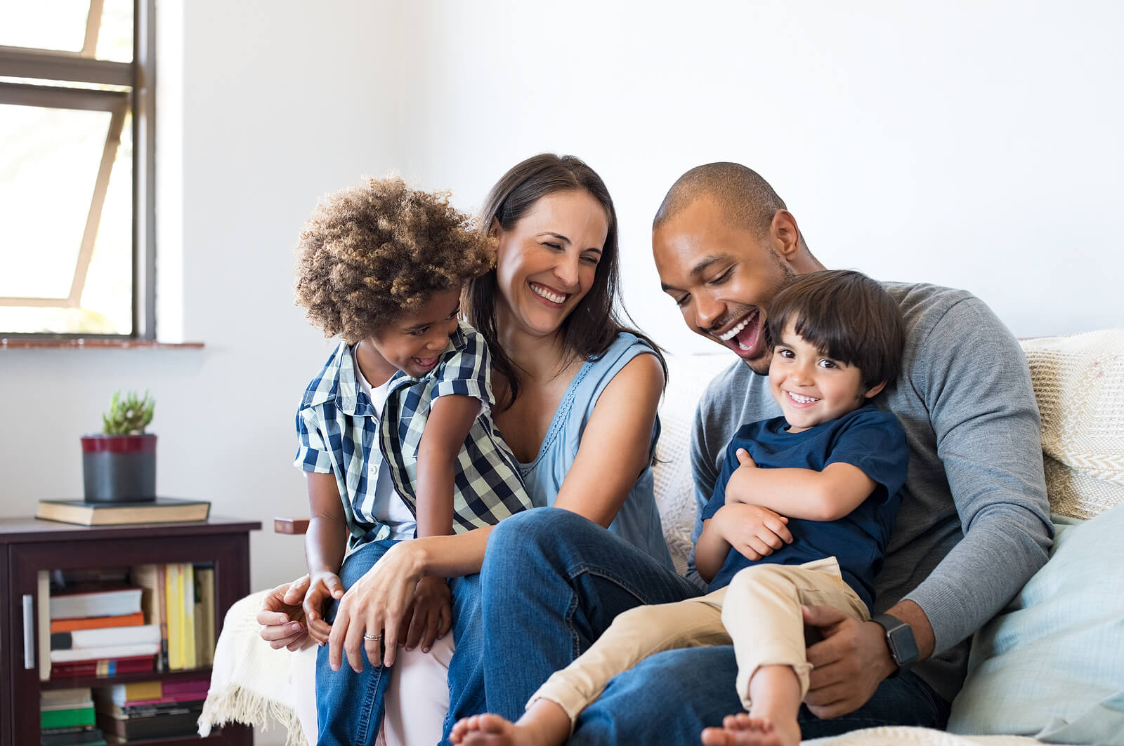 Happy parents sitting on a couch holding two young boys. Watch your child heal from emotional and behavioral challenges in positive ways and see their confidence soar with therapy for children in South Jersey.