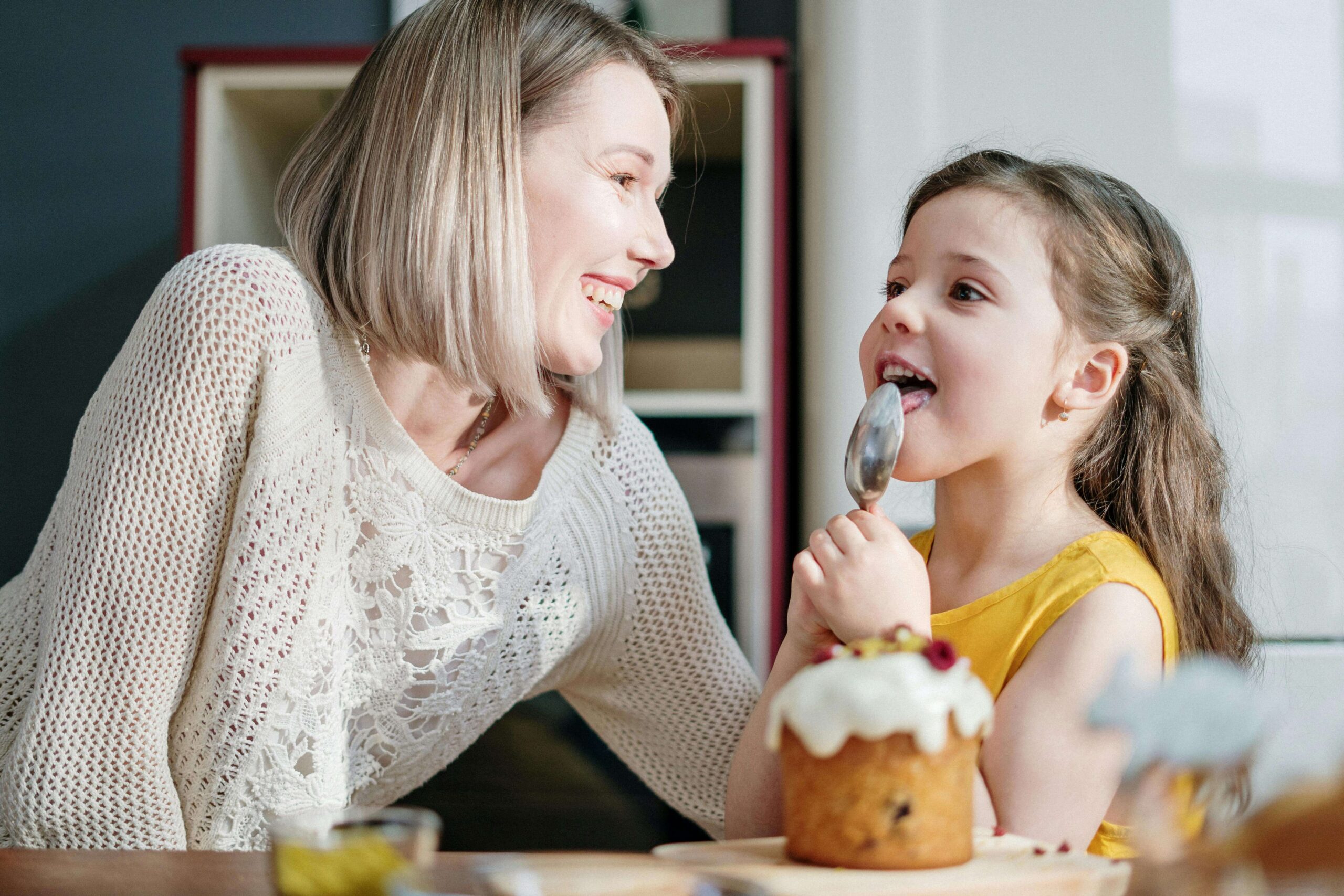 Smiling mother looking at her young daughter licking a spoon. By working with a child therapist in South Jersey, you can begin to see your child heal from their anxiety, depression, and more. Reach out to start seeing your child thrive!