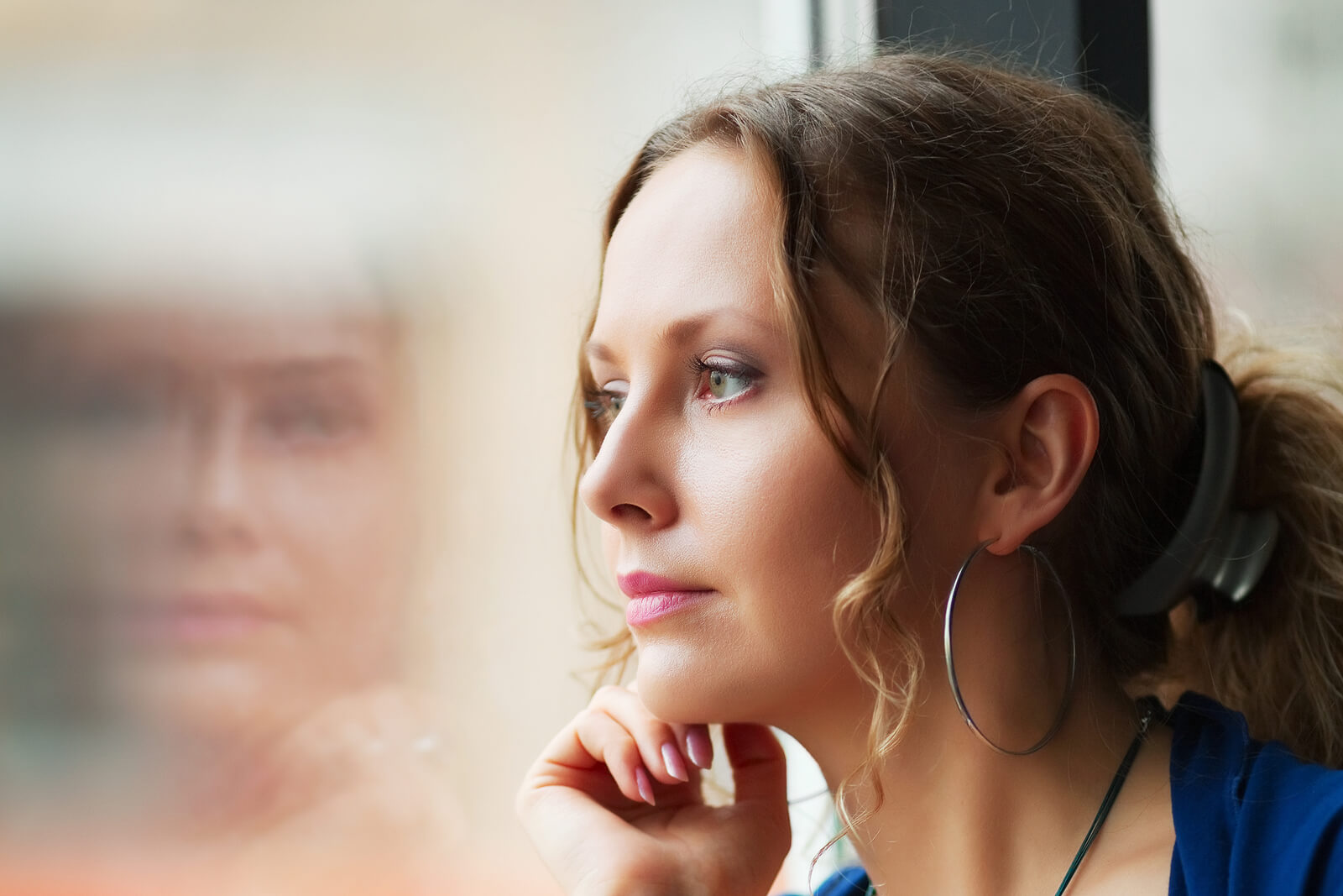 Thoughtful woman sitting next to a window looking out. Begin to find a deeper understanding of yourself and learn to overcome challenges with an ADHD assessment in South Jersey.
