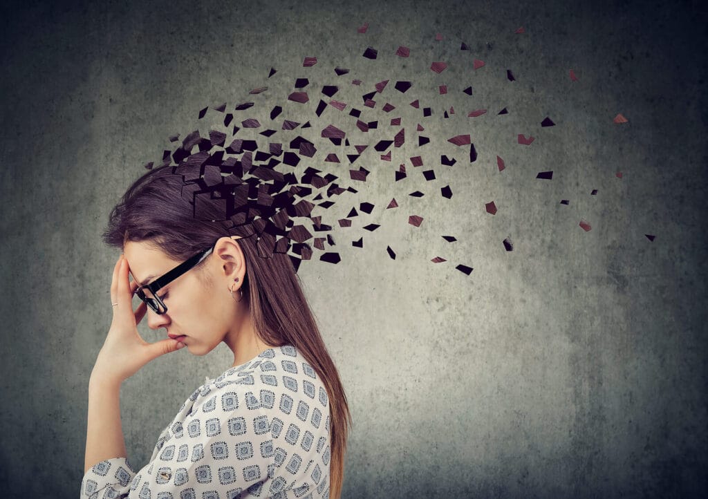 Woman covering her face with her hand as pieces come out of the back of her head. With ADHD testing in South Jersey you can discover your unique traits and navigate them with ease.