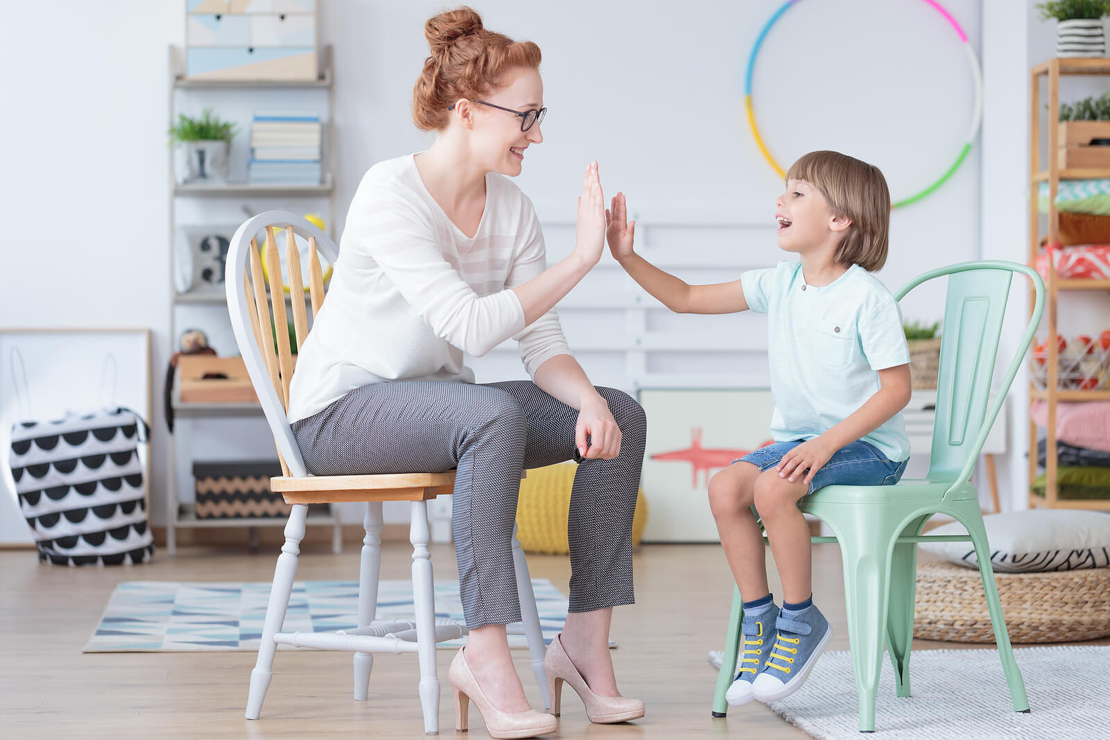 A child shares a joyful high-five with a therapist during a supportive session. Autism testing in South Jersey opens the door to personalized autism therapy and the guidance of a neurodivergent affirming therapist to help children thrive.