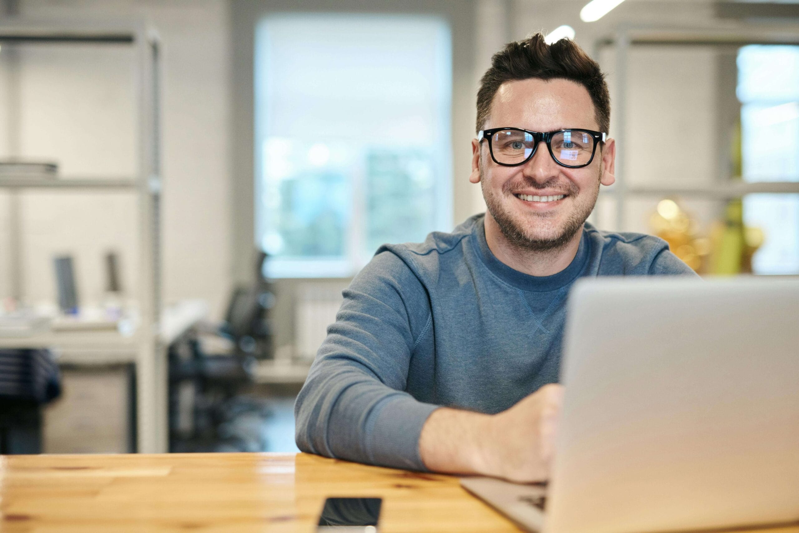 Smiling man working at a laptop in a bright office. Start building confidence and balance with a neurodivergent affirming therapist through ADHD testing in South Jersey.