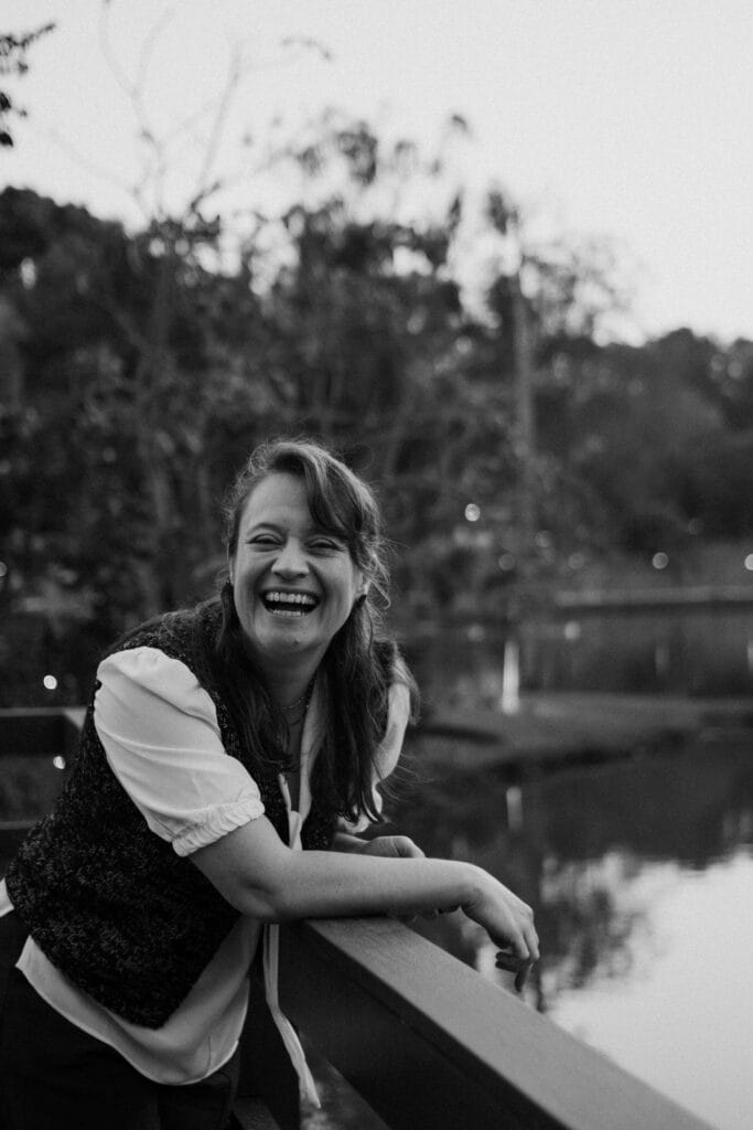 Happy woman laughing while leaning on a railing outdoors. Begin to embrace your strengths as an adult through ADHD testing in South Jersey.