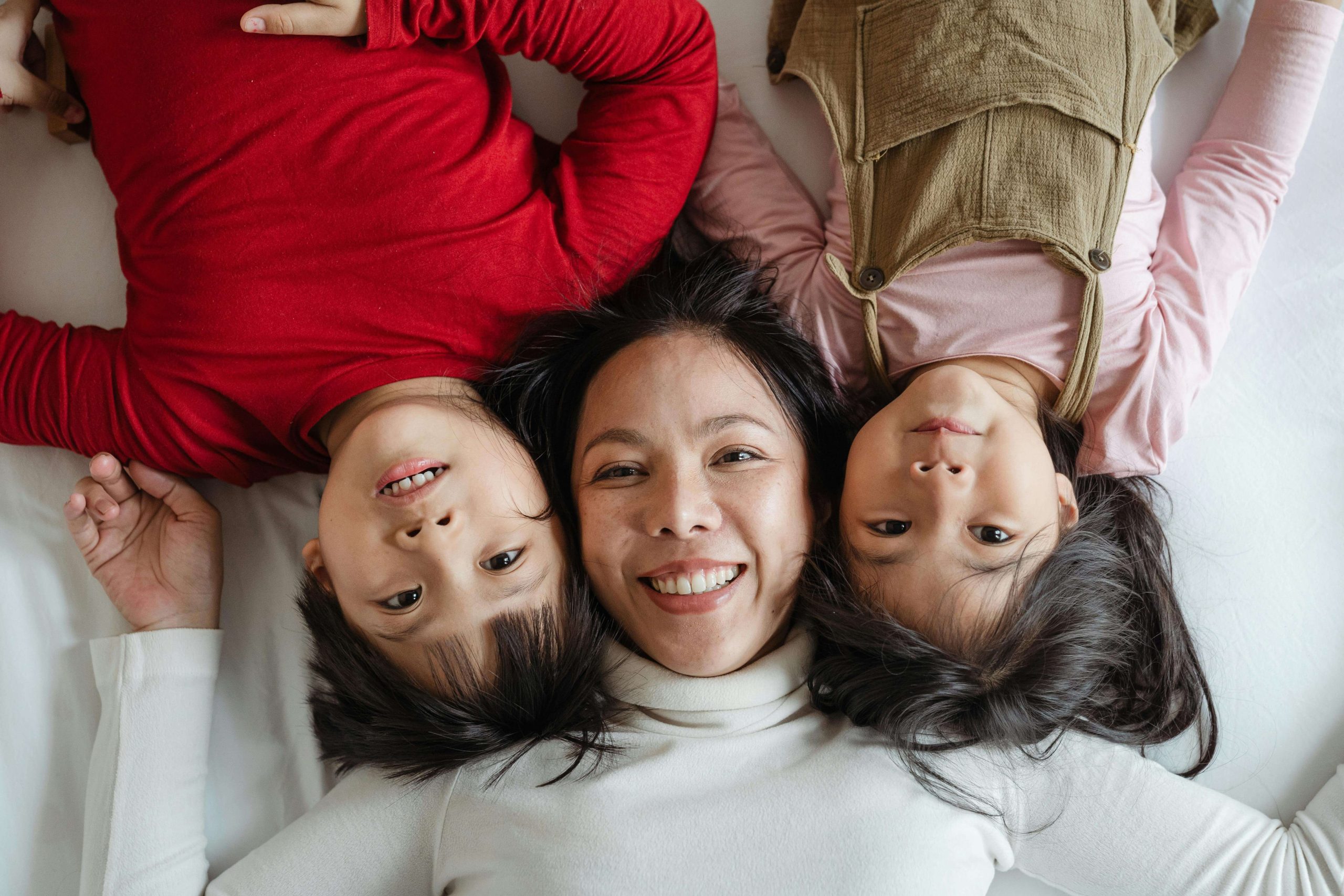 A happy mother laying on the bed with her two young children smiling and cuddling close. See your child gain clarity and confidence through autism testing in South Jersey, supported by compassionate autism therapy and family-centered care.