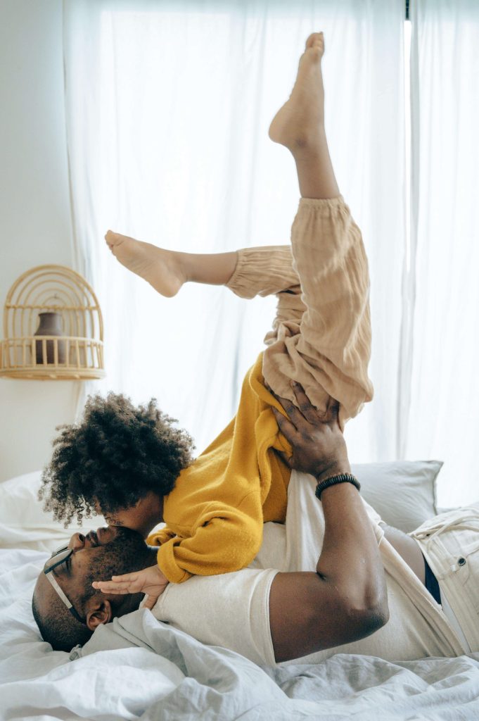 A father lifts his laughing child in the air during playful bonding time at home. With autism testing in South Jersey, families can access early autism assessments and neurodivergent therapy that nurture resilience and connection.
