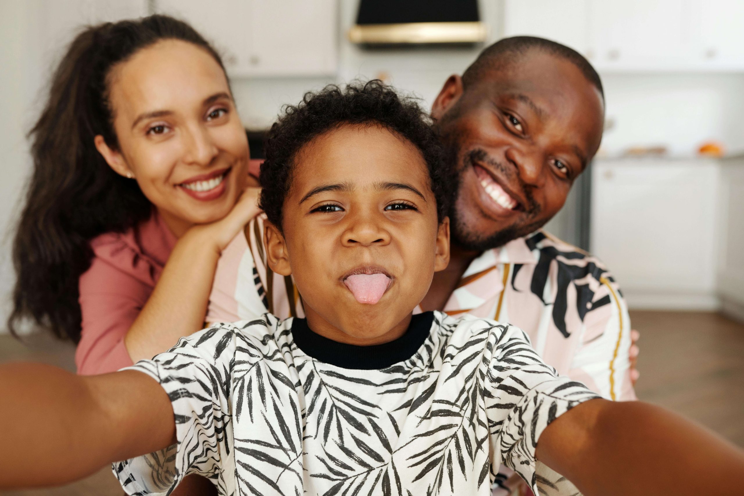 Smiling parents sit behind their playful child taking a selfie. Early ADHD testing in South Jersey helps families understand challenges, while a neurodivergent affirming therapist can provide tools for growth and resilience.