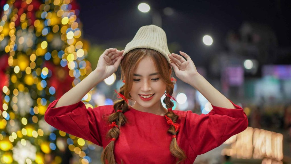 Woman putting a stocking cap on with holiday lights in the background. Get through the hard times during the holidays with the help of the best therapists in New Jersey. DBT Therapy near Moorestown, NJ or Voorhees, NJ is here for you all year.