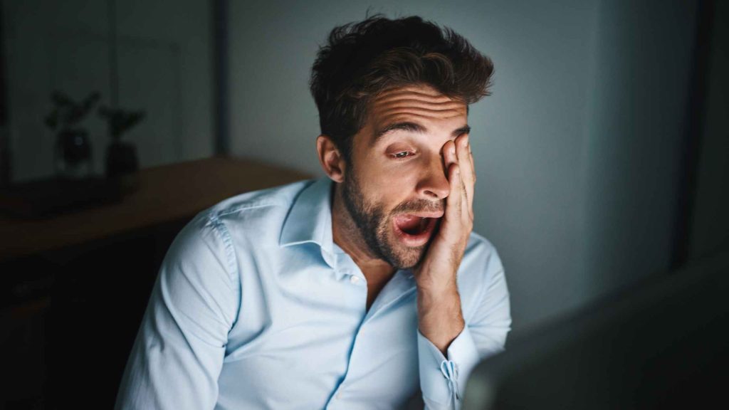 Yawning man at a computer screen, trying to stay awake for therapy. Daytime Therapy in New Jersey might be the best option!
