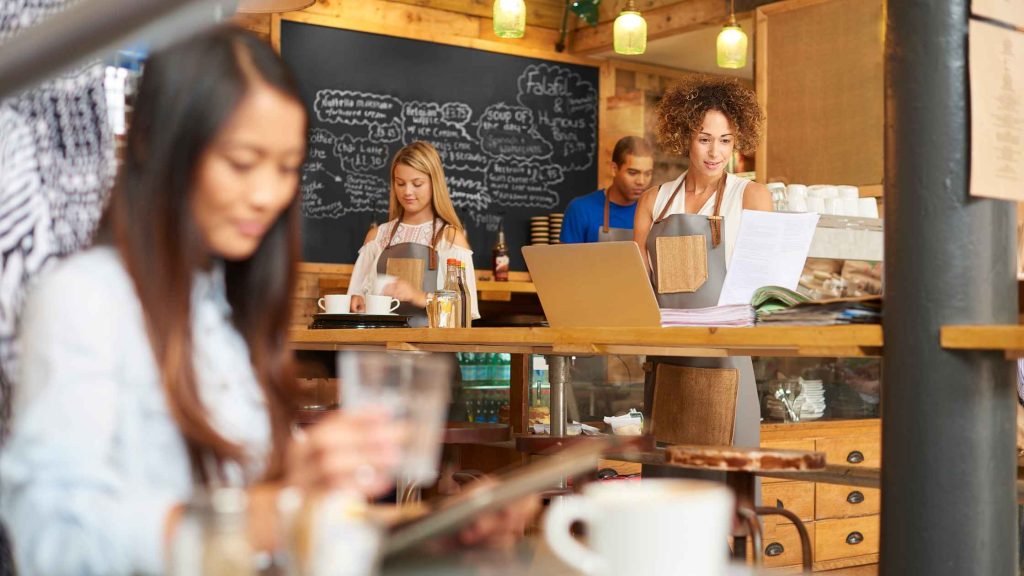 Three women share coffee and conversation in a busy cafe, the kind of social setting autistic, ADHD, and AuDHD adults often navigate with support from DBT of South Jersey.