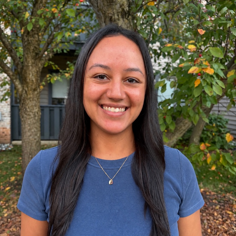 Alexis Farr, LAC, a DBT therapist in Moorestown, NJ, smiling outdoors in a blue top in front of trees.