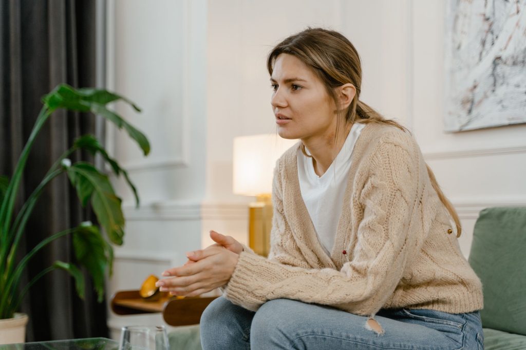 Woman in a cream cardigan sits on a sofa and talks with her therapist, representing individual therapy for relationship stress when a partner will not attend couples therapy at DBT of South Jersey in Voorhees and Moorestown, NJ